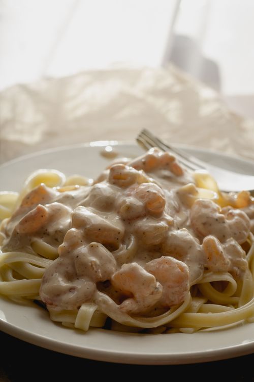 Free Delicious creamy shrimp pasta served on a white plate with natural light. Stock Photo