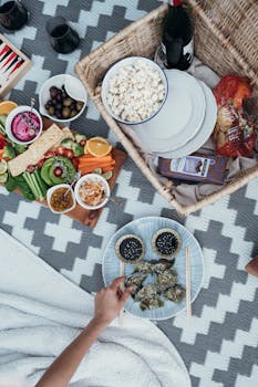 A colorful picnic setup featuring dumplings, popcorn, and fresh vegetables, perfect for a relaxing outdoor meal.