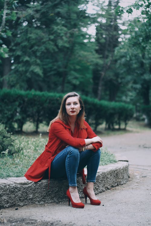 Free Woman in Red Coat Sitting on Gutter Stock Photo
