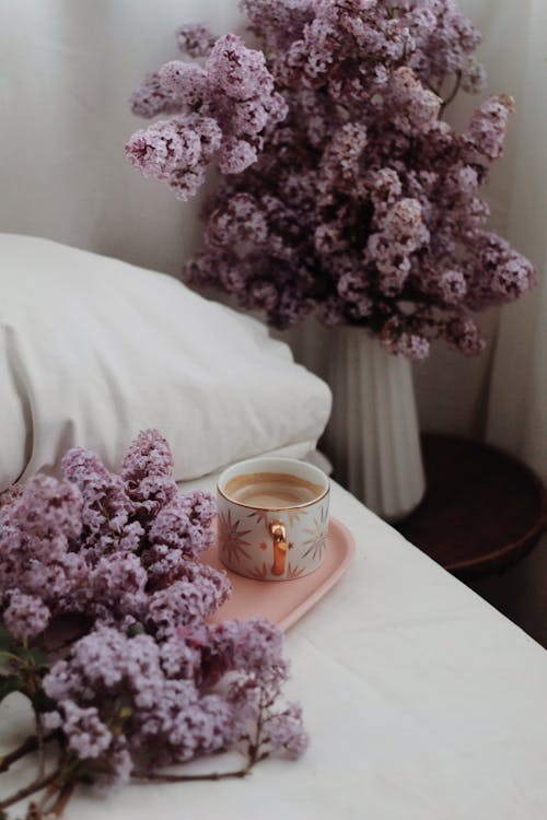 Bouquets of lilacs in bedroom near cup of coffee