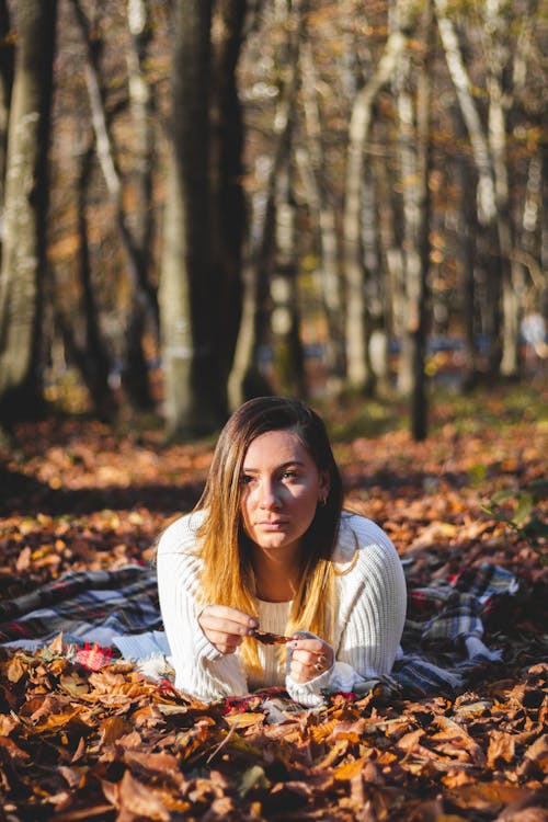 Free A Woman in a Knitted Sweater Lying on the Ground Stock Photo