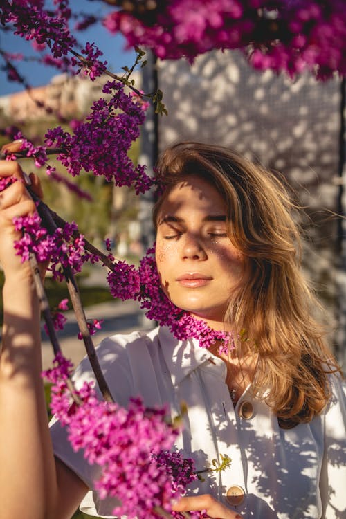 Free A Woman with her Eyes Closed Beside Flowers Stock Photo