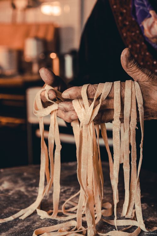 Free Artisan hands crafting fresh pasta in a warm, cozy kitchen setting. Stock Photo