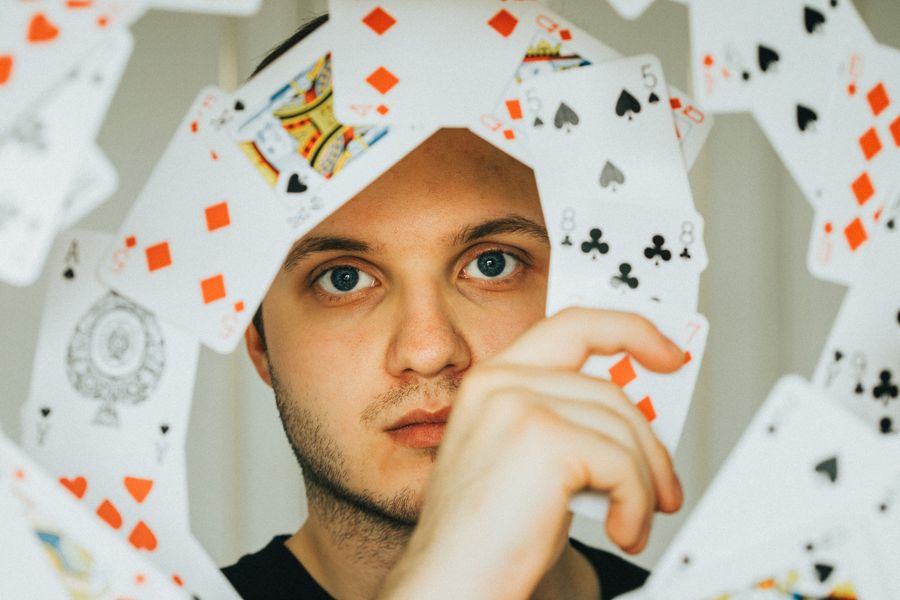 Portrait of a card handler behind a fan of playing cards — photo by Ryan Link on Pexels