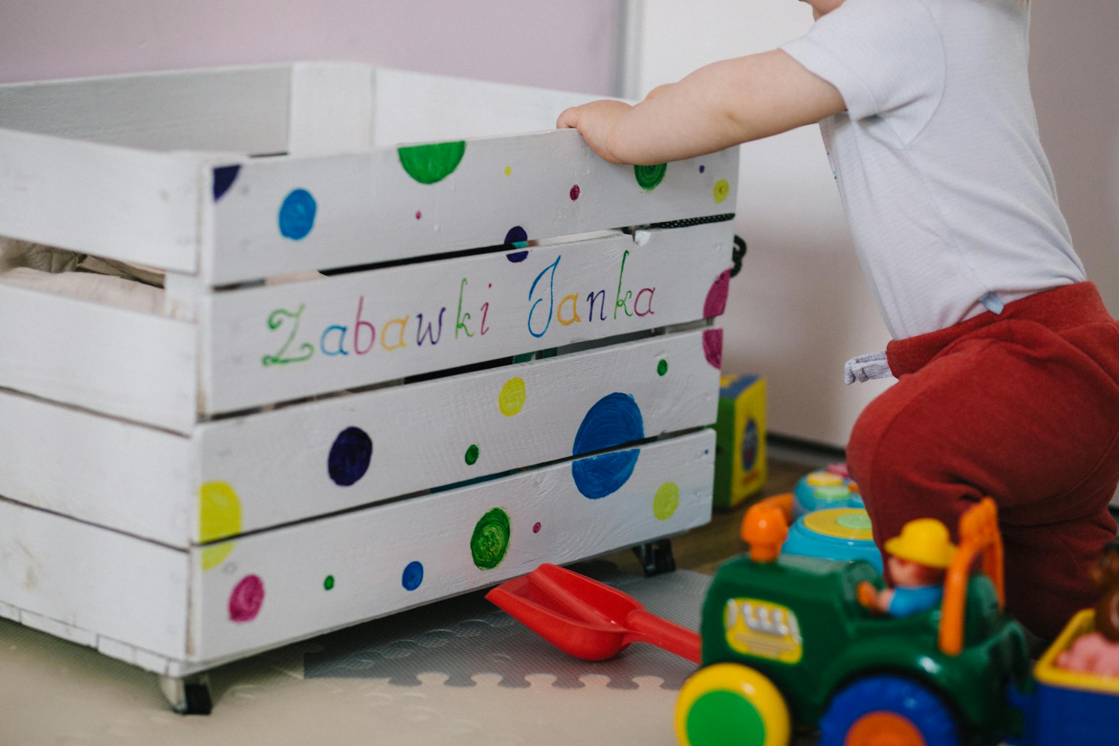 A child picking their toys from a toy chest.
