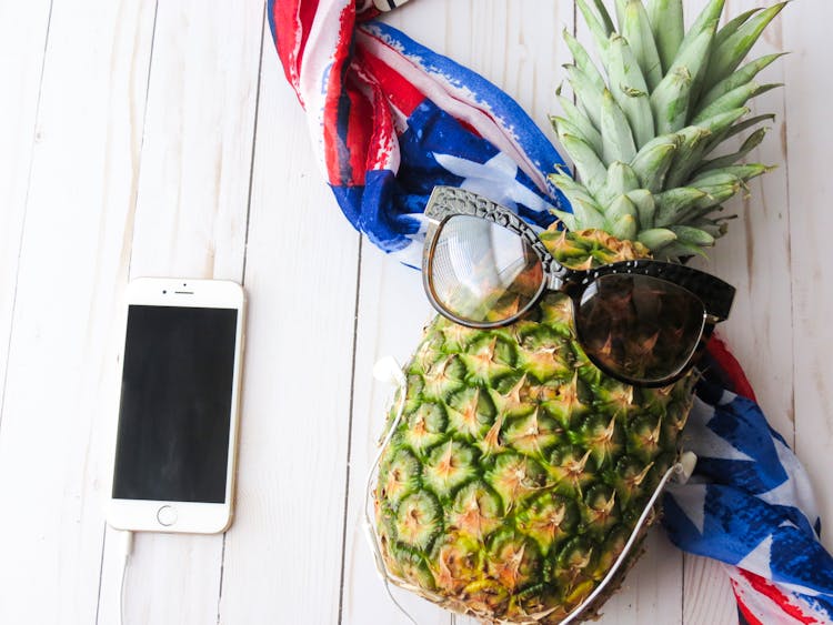 Ripe Pineapple With Brown Sunglasses Near Gold Iphone 6 On White Surface