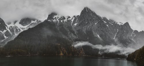 Snowy Mountain Near a Lake Under a Foggy Sky