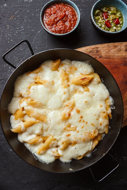 Appetizing penne pasta with processed cheese near sauces