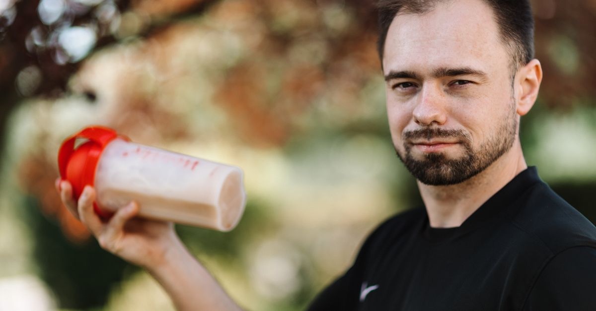 Adult man holding a protein shake outdoors during the day. - Evidence evidence guide for whey protein muscle recovery randomized trial