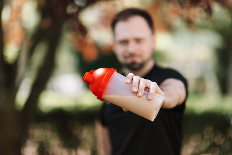 A Plastic Tumbler With Drink On A Man's Hand