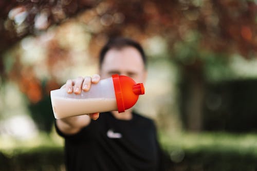 Botella con el batido de proteínas sobre fondo blanco Fotografía