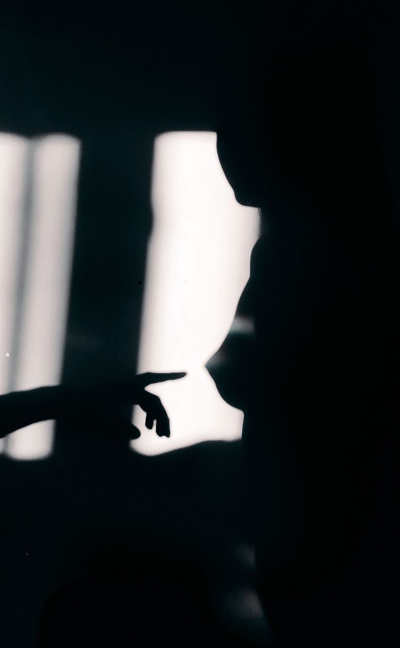 Side view of black and white anonymous naked woman standing in dark bedroom near crop boyfriend