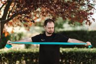 一名男子在阳光明媚的户外用阻力带锻炼