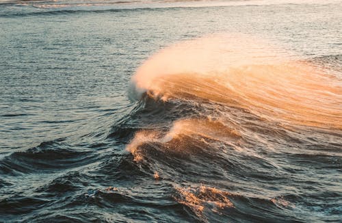 Free Amazing scenery of foamy waves of stormy ocean splashing near coast during sunset Stock Photo