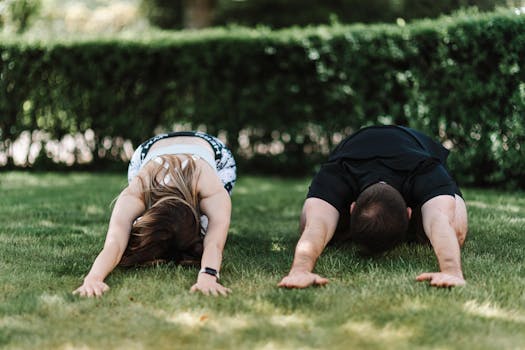 A couple practicing yoga outdoors in child's pose, enjoying nature and fitness.