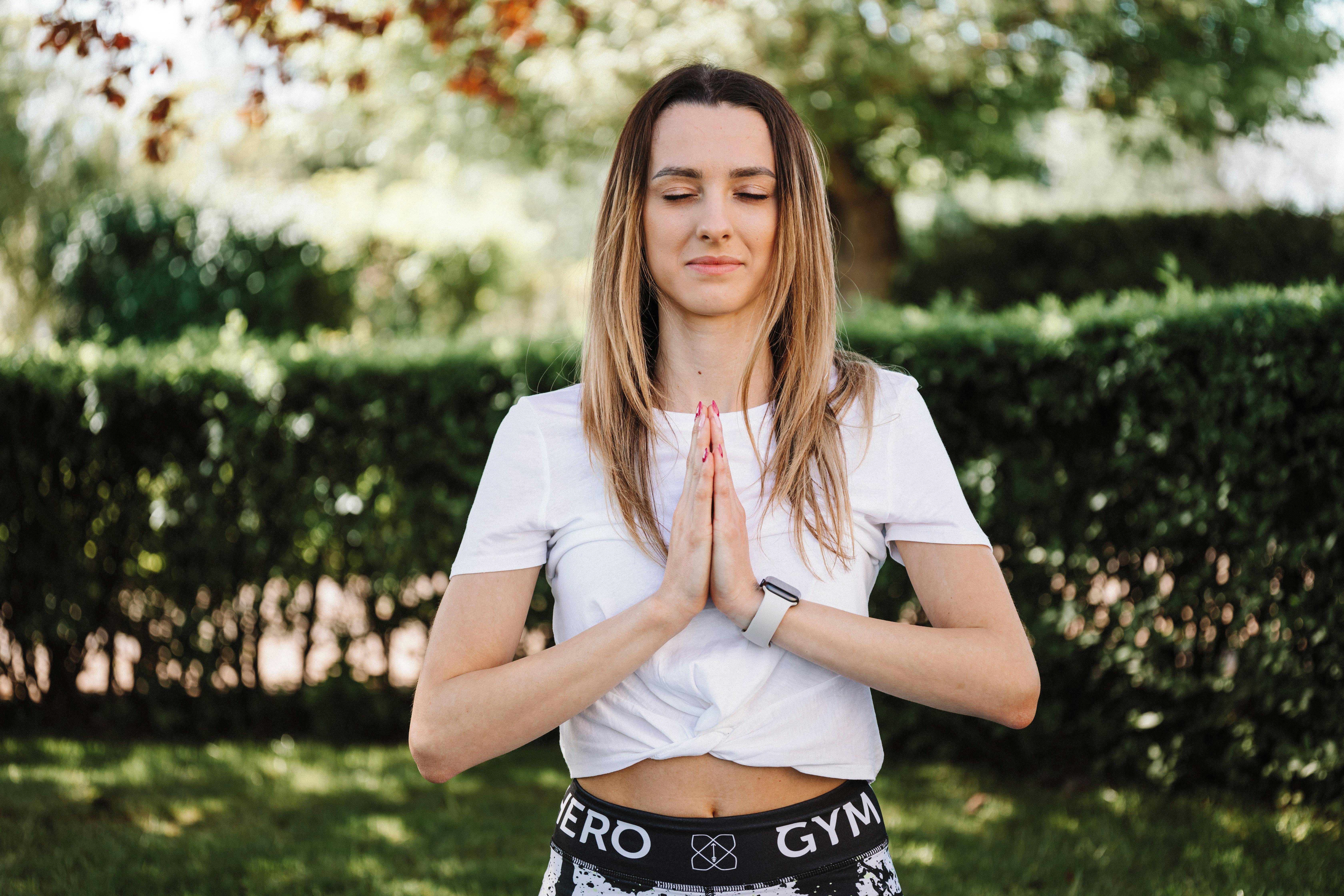 A serene moment of a woman practicing yoga with namaste pose outdoors, embracing mindfulness.