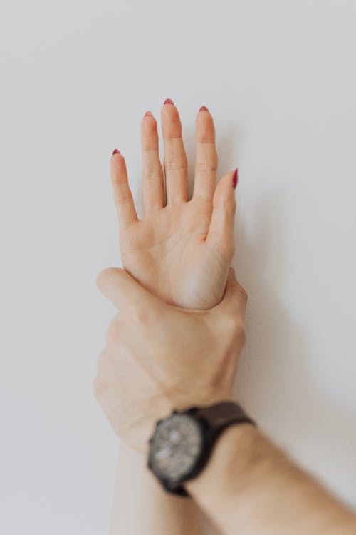 Man Hand Oppressing a Hand of a Woman on the Wall