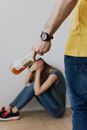 Man Holding a Bottle Near a Woman Sitting Covering Her Face