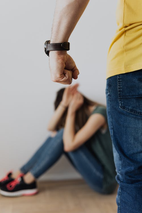 Free Man in Yellow Shirt and Blue Denim Jeans Clenching Fist Near a Woman in Green Top Stock Photo