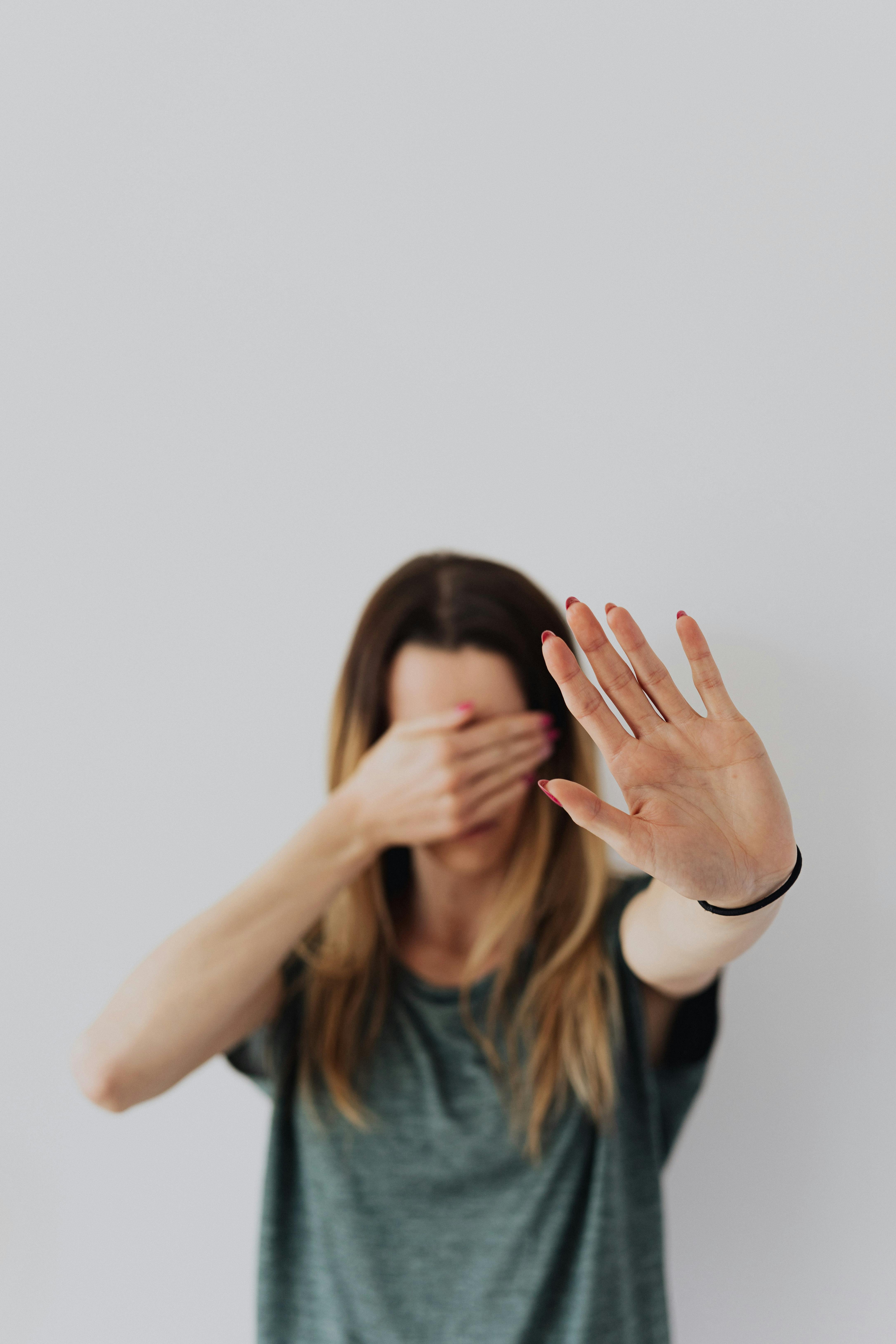 Free A Woman Covering Her Face with Hand and Showing a Stop