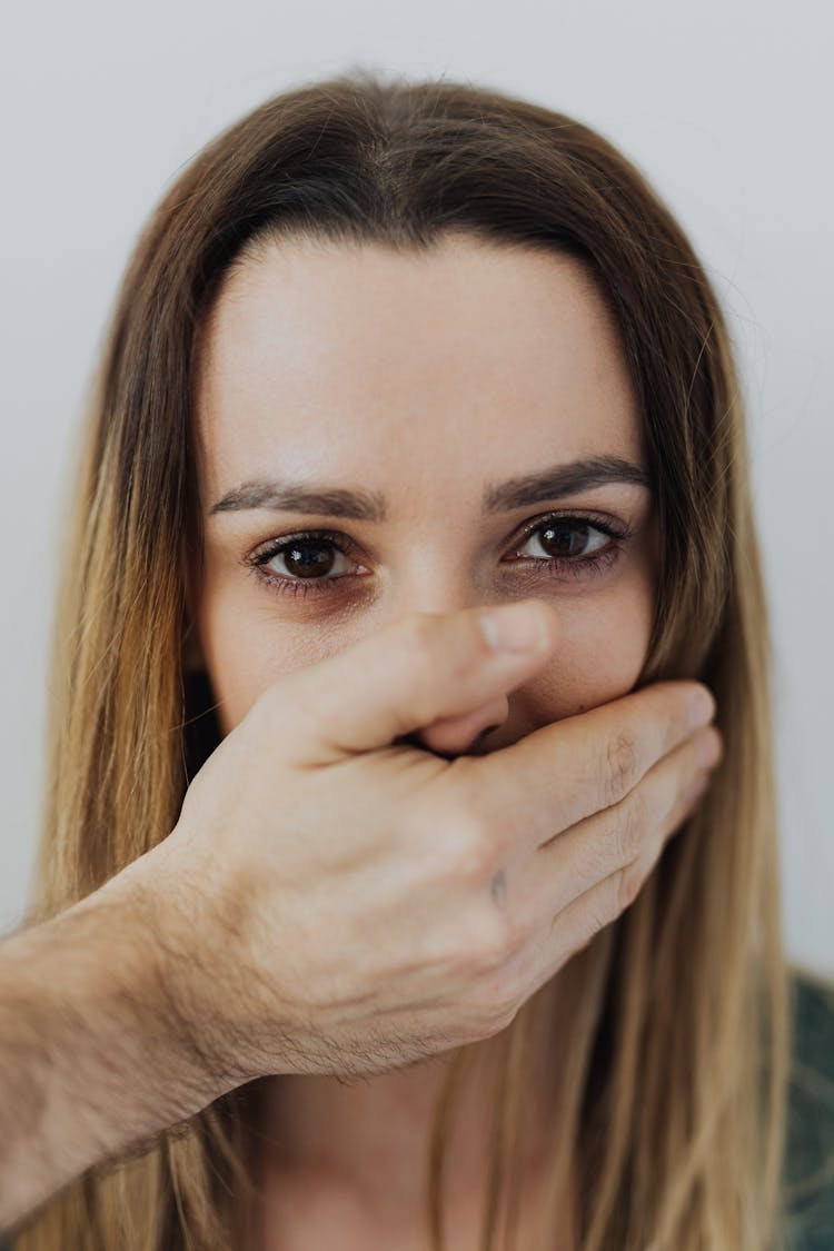 Hand Of A Man Covering The Mouth Of A Woman