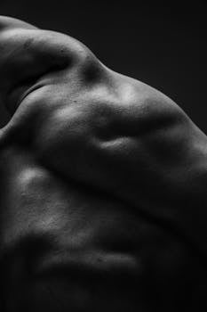 Dramatic black and white close-up of a muscular male back showcasing strength and texture.