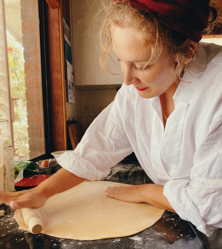 Woman In White Long Sleeves Shirt Rolling A Pizza Dough
