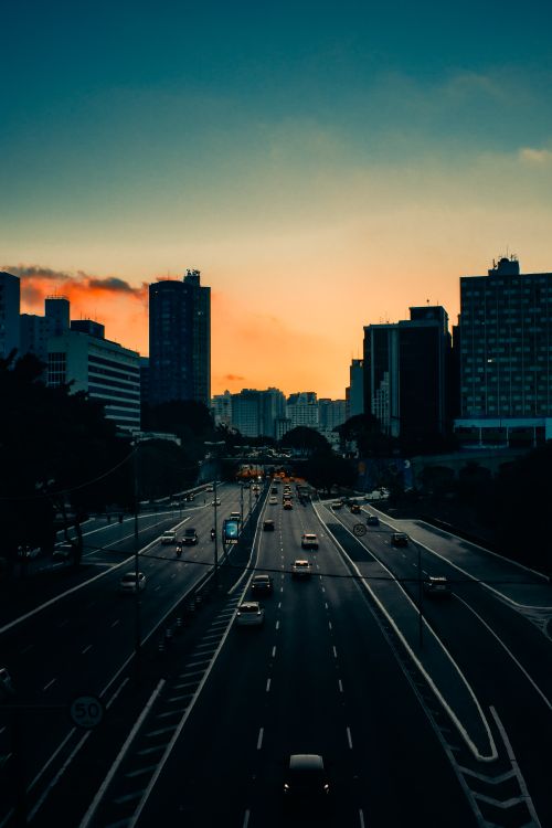 Free From above of various vehicles riding along asphalt road in city downtown against colorful sunset sky Stock Photo