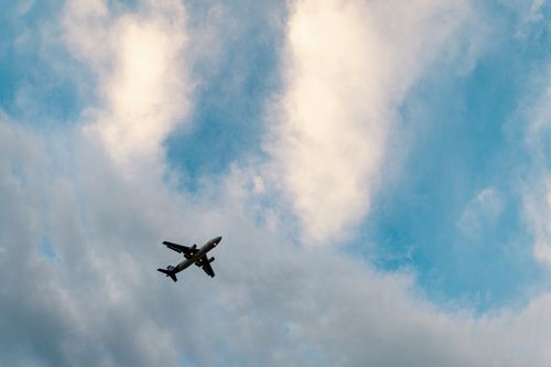 Free From below of modern airplane flying in cloudy blue sky on sunny day Stock Photo