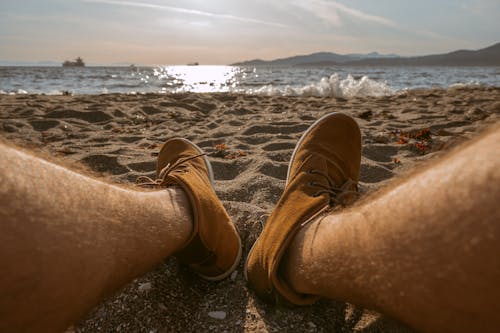 A Person Wearing Brown Shoes on the Beach