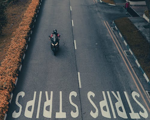 Faceless person riding modern motorbike on street
