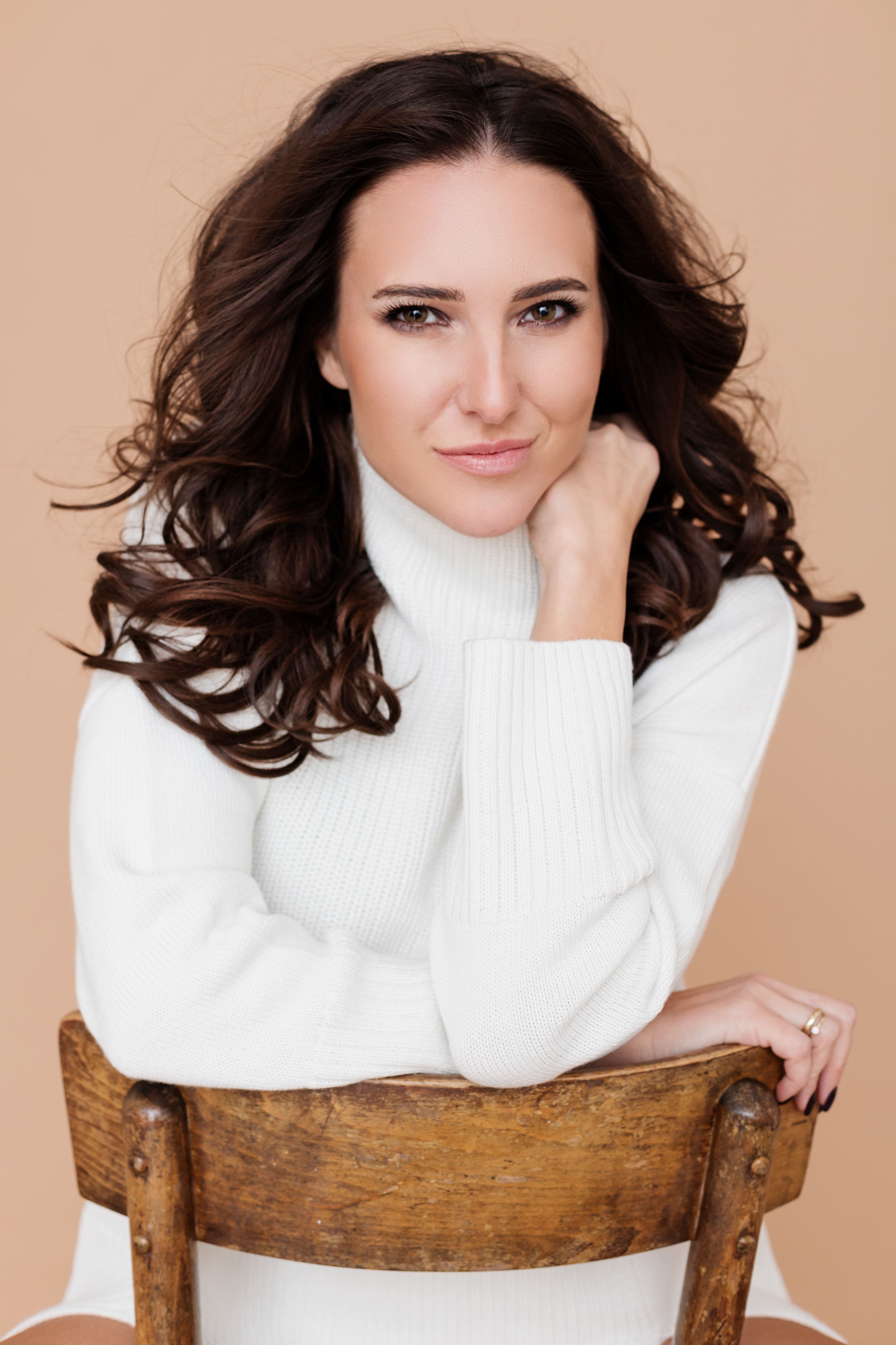Portrait of a woman in a white turtleneck posing on a wooden chair. Ideal for fashion and lifestyle content.