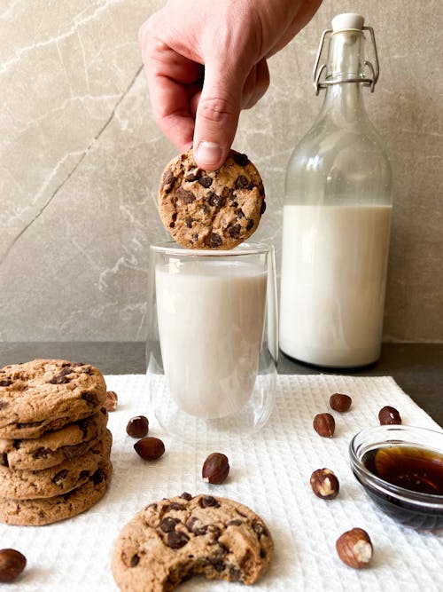 Free Person Holding a Cookie Near a Glass of Milk Stock Photo