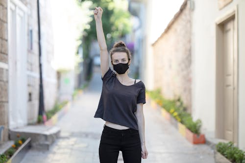 Free Woman in Black Shirt and Black Pants Raising Her Arms Stock Photo