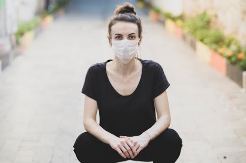 Free Woman in Black Shirt and White Face Mask Sitting on the Ground Stock Photo