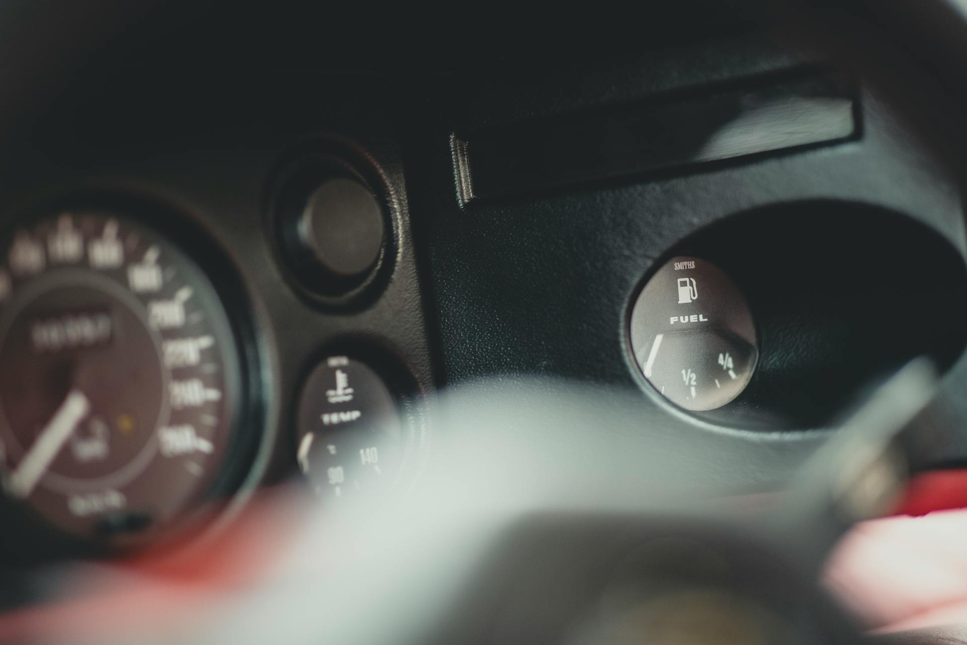 Close-up shot of vintage car gauges showing fuel level and odometer readings.
