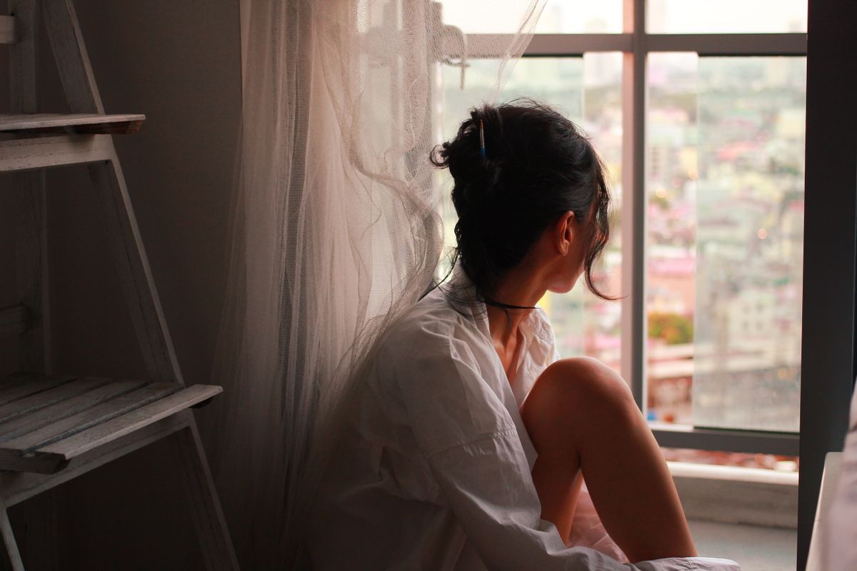 A woman sitting quietly by a window in soft light