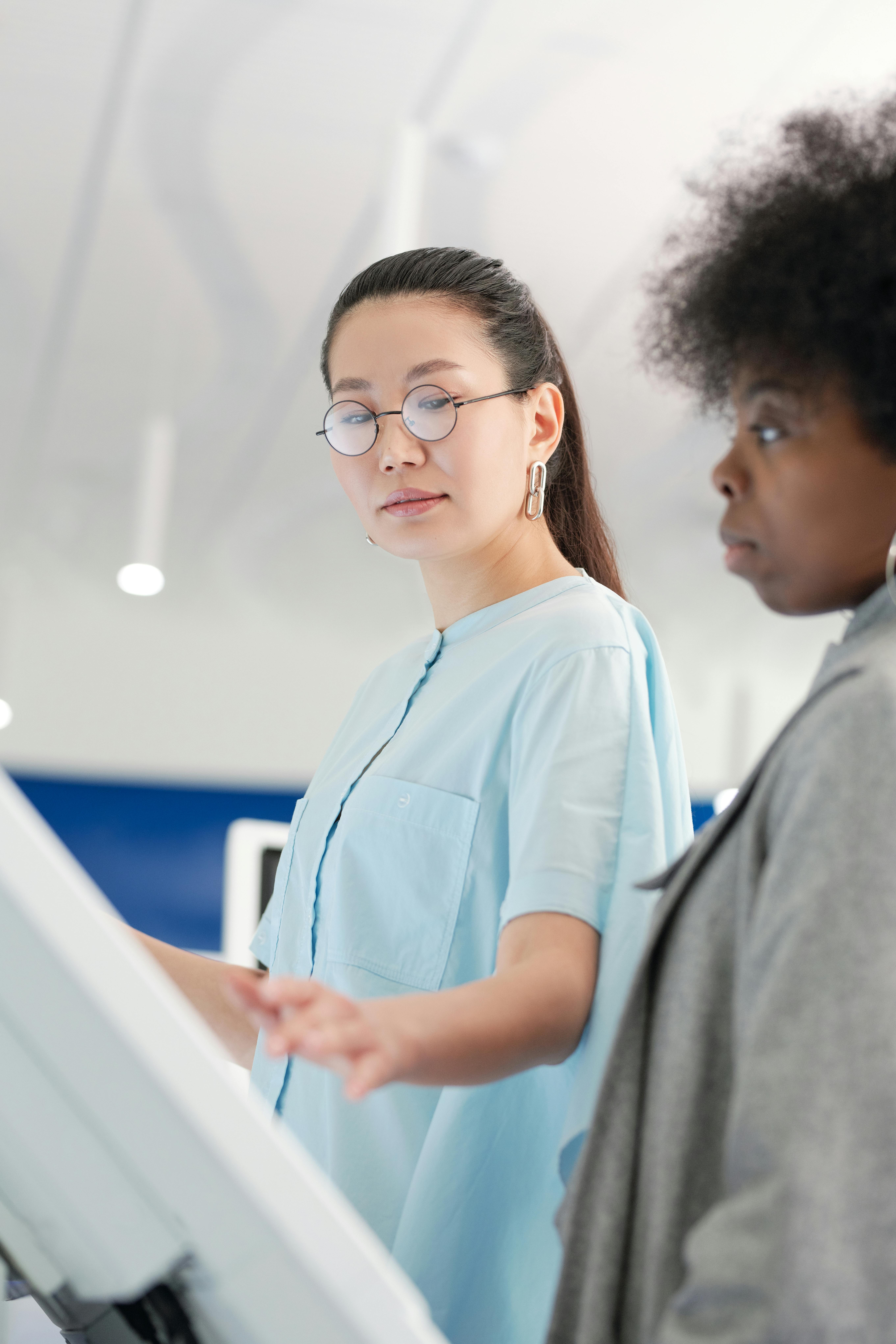 在明亮的室内环境中，两名女性通过触摸屏进行互动，凸显了协作