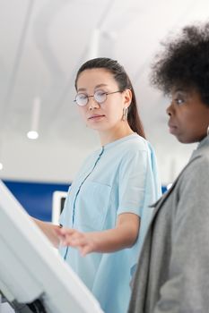 在明亮的室内环境中，两名女性通过触摸屏进行互动，凸显了协作