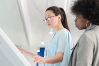 在现代室内环境中，两位不同的女性正在使用交互式屏幕
