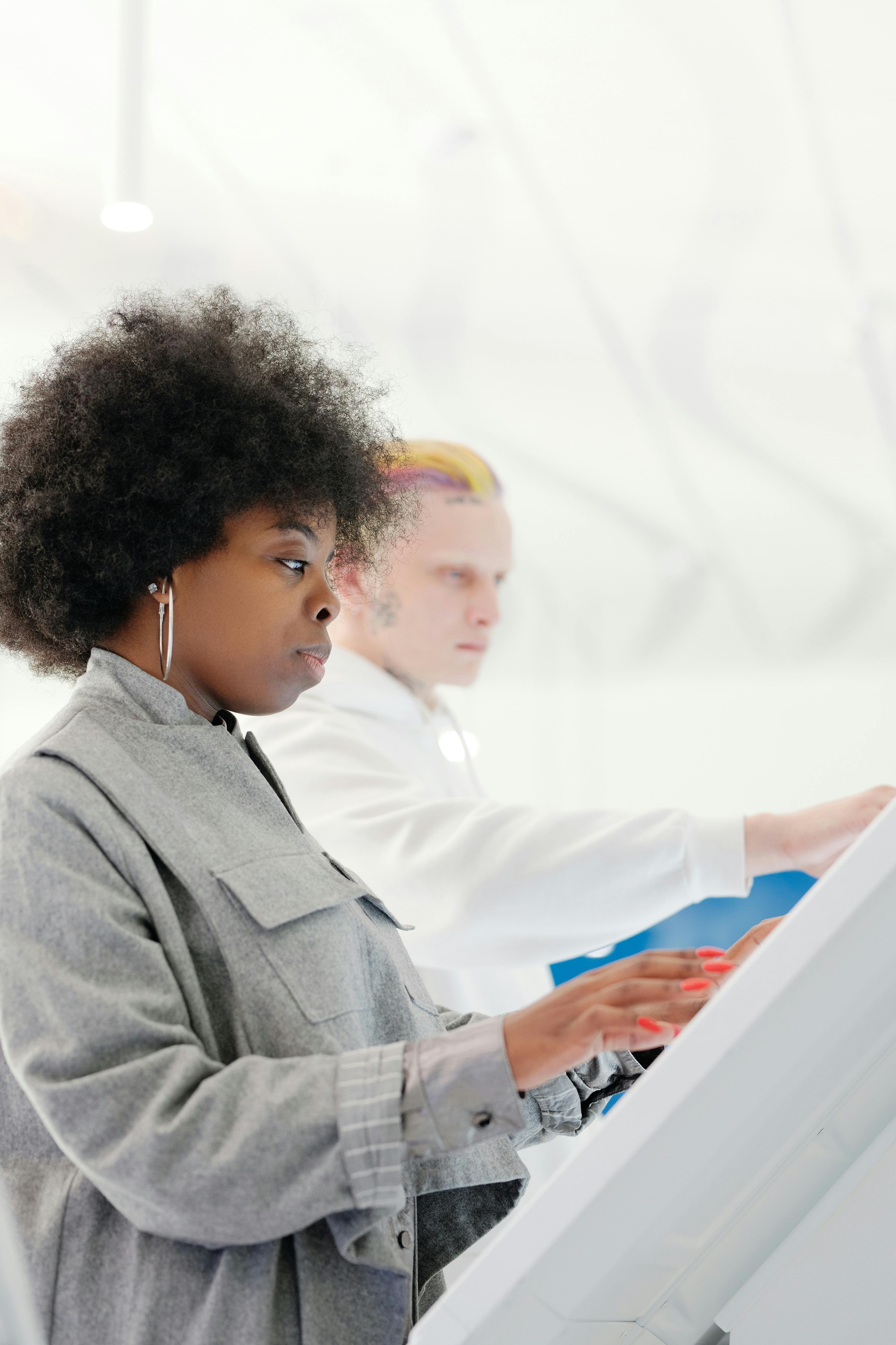 在室内，一位留着非洲发型的时尚女性被触摸屏拍摄了侧面图