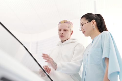 Free Two people engaged in a discussion, using a touchscreen in a modern white office. Stock Photo