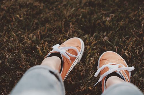 Free Close-up of stylish orange sneakers on green grass, showcasing casual outdoor fashion. Stock Photo