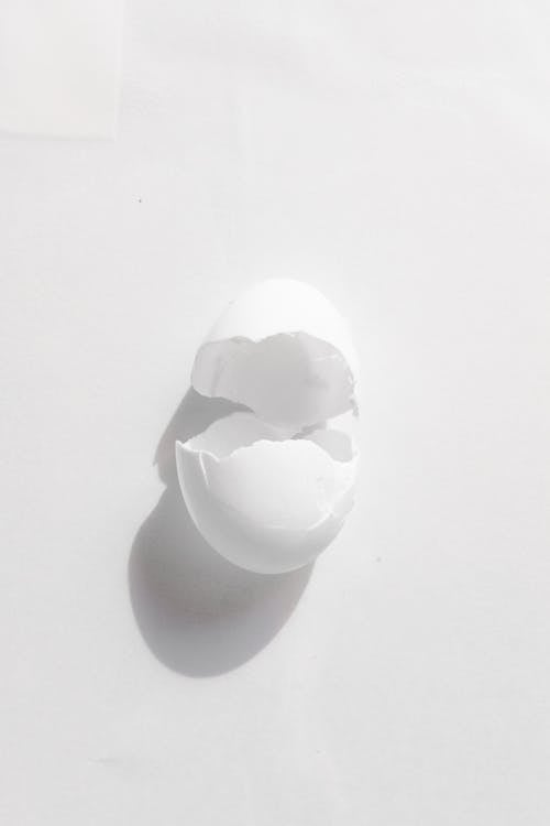 Cracked shell of chicken egg on white surface