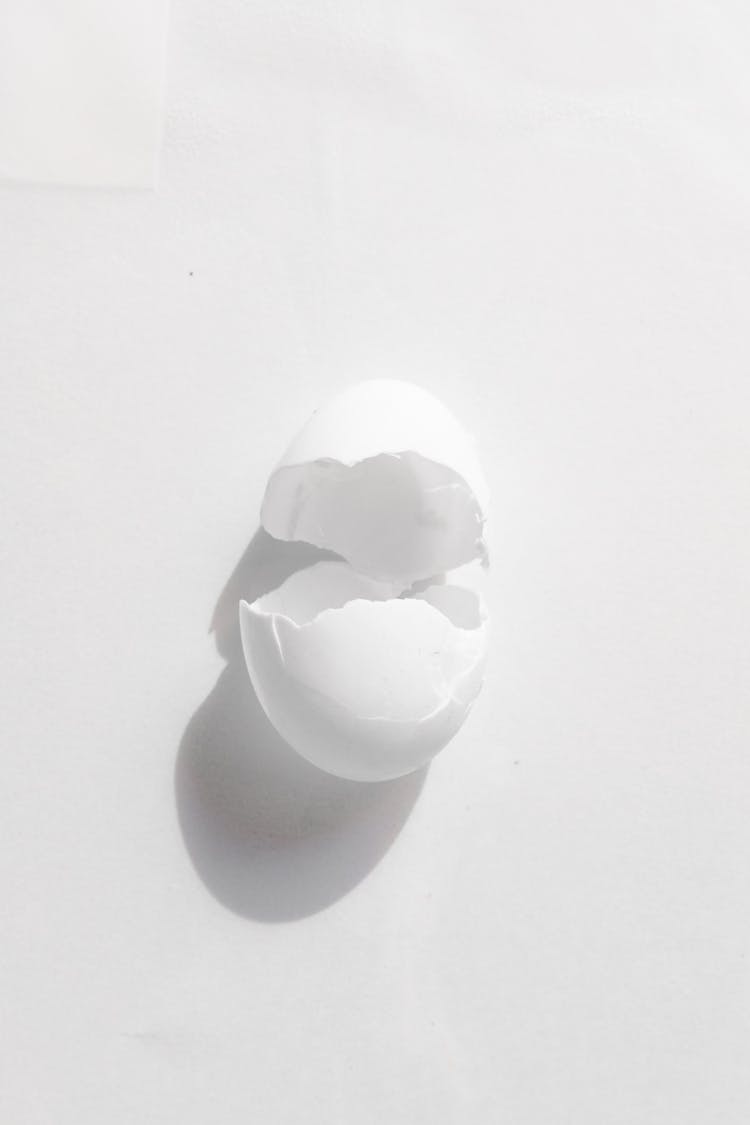 Cracked Shell Of Chicken Egg On White Surface