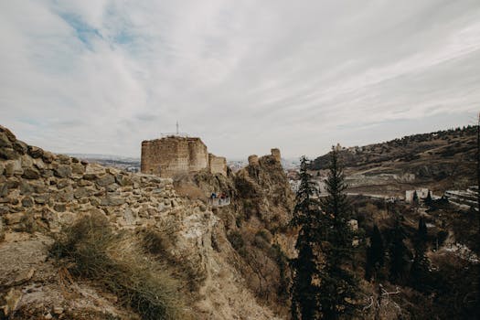 Stunning aerial shot of the ancient Narikala Fortress against a cloudy sky in Tbilisi, Georgia.