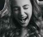 Close-up of a woman with wavy hair exhibiting joy in black and white.
