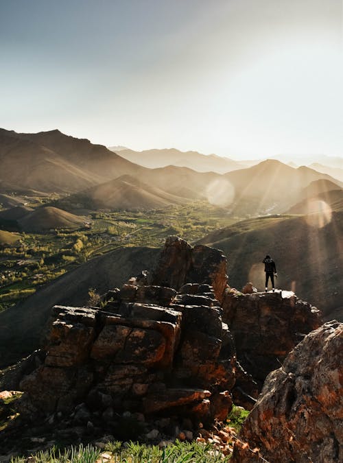 Traveler on rock observing mountains in sunny day