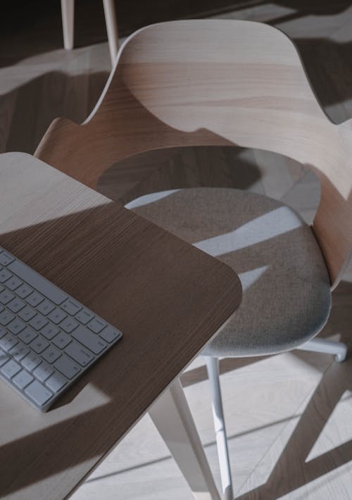 A Computer Keyboard on a Wooden Table Near an Armchair