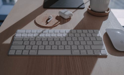 A Keyboard, Mouse and Wireless Headphones on a Wooden Table Top